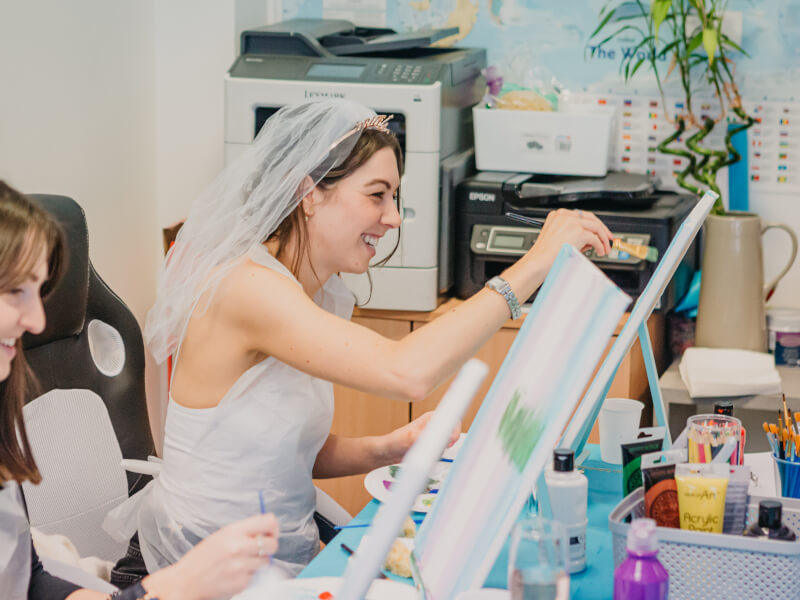 Woman in white dress and veil painting on a canvas